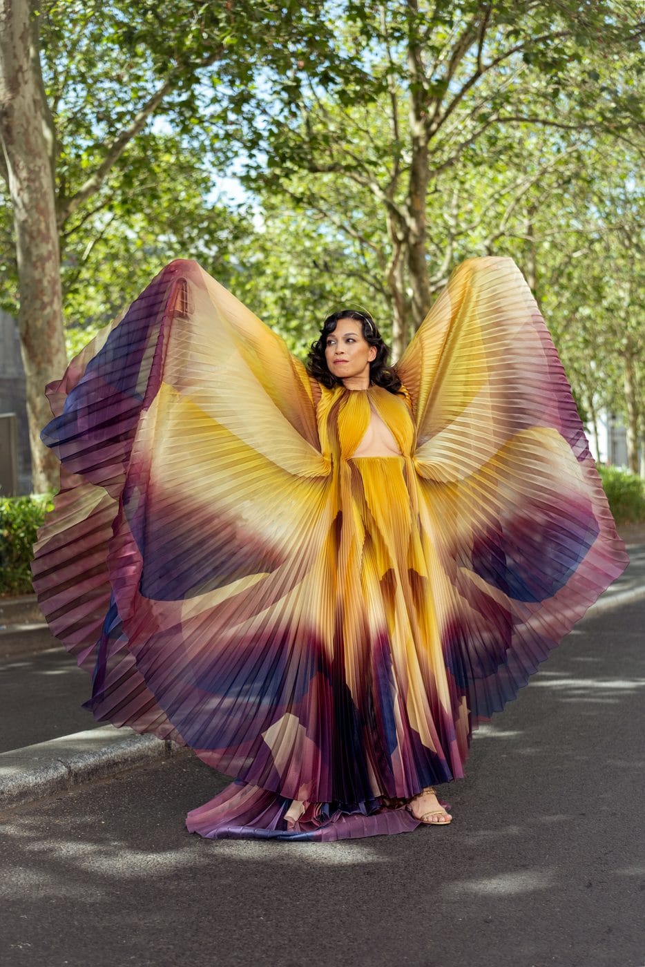 Woman in an outstretched yellow and purple butterfly cape beneath trees, Jennifer JJ Lee (@by.jjlee), Iris van Herpen