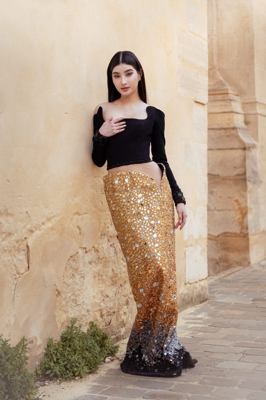 Woman in a black top and long gold sequined skirt against cut stone, Mable Siriwalee (@mable_siriwalee), Tony Ward Couture