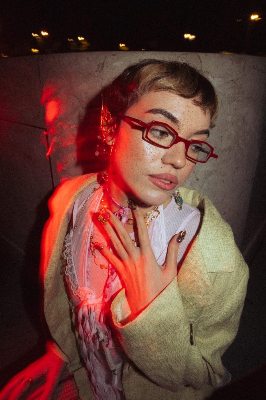Portrait lit in red neon, woman in red glasses and a printed scarf