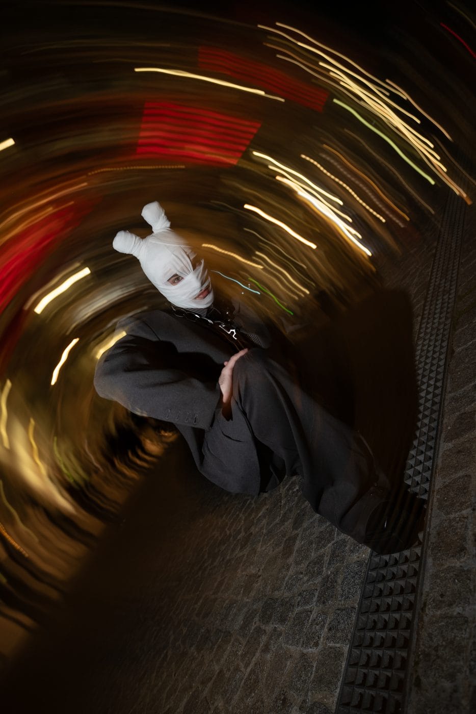 Long-exposure spin, a seated figure held still inside a swirl of amber and red light
